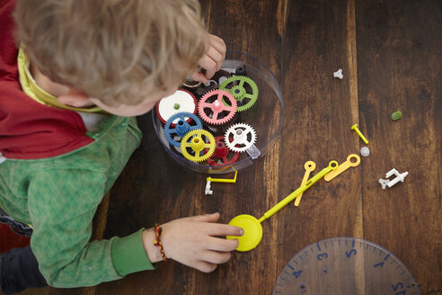 Blonder Junge beim Zusammenbau einer Spielzeuguhr - RHF000758
