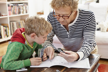 Grandfather and grandson assembling toy weather station - RHF000759