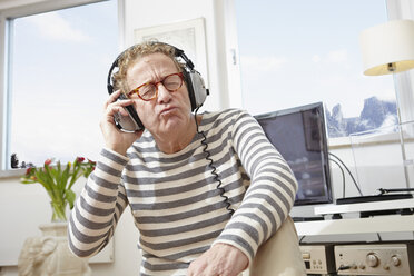 Senior man wearing headphones, listening to music - RHF000767