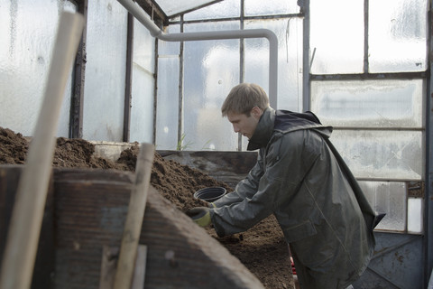 Junger Gärtner bei der Arbeit, Mutterboden auffüllen, lizenzfreies Stockfoto