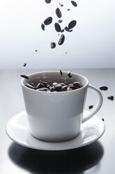 Kaffeebohnen fallen in eine weiße Kaffeetasse - BZF000134