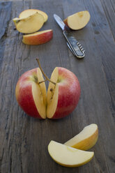In Scheiben geschnittene Äpfel und Taschenmesser auf dunklem Holz - CRF002678