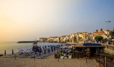 Italien, Sizilien, Cefalu, Blick auf mittelalterliche Häuser mit Strand im Vordergrund in der Abenddämmerung, lizenzfreies Stockfoto