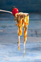 Gekochte bunte Linguini und rohe Kirschtomaten auf einer Gabel - CSF025307