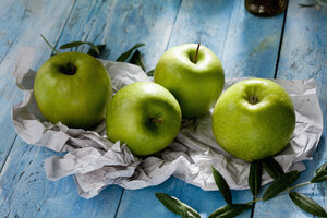 Vier Granny Smith und Olivenzweige auf Papier - CSF025319