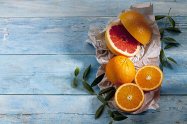 Sliced pink grapefruit, whole and sliced oranges on paper - CSF025321