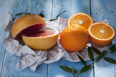 Rosa Grapefruit in Scheiben, ganze und in Scheiben geschnittene Orangen auf Papier - CSF025322