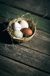 Easter nest with eggs in bowl on dark wood - MAEF010242