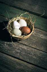 Osternest mit Eiern in Schale auf dunklem Holz - MAEF010242