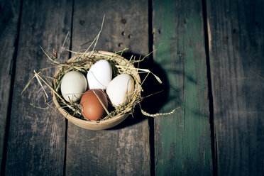 Easter nest with eggs in bowl on dark wood - MAEF010243