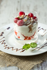 Dessert im Glas mit Himbeeren, Quark, Joghurt, getrocknetem Apfel, Mandelsplittern und Schokoladensauce - MAEF010262