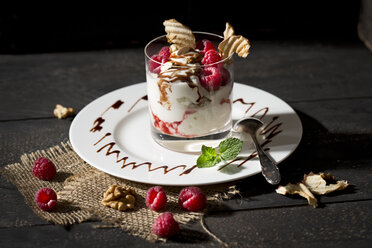 Dessert in glass with raspberries, curd, yoghurt, dried apple, almond slivers and chocolate sauce - MAEF010264