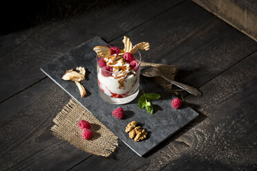 Dessert in glass with raspberries, curd, yoghurt, dried apple, almond slivers and chocolate sauce - MAEF010266