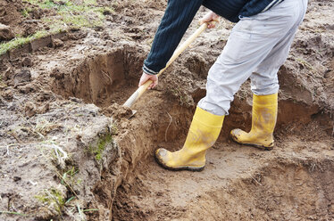 Man digging out a plant terrace of a pond - HAW000790