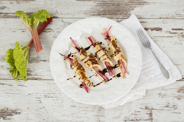 Rhubarb in puff pastry with almond slivers and chocolate sauce on plate - MAEF010278