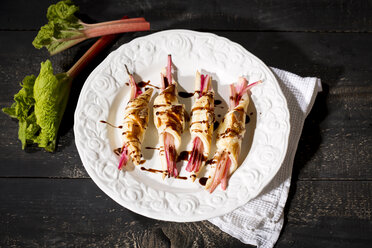 Rhubarb in puff pastry with almond slivers and chocolate sauce on plate - MAEF010281