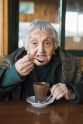 Porträt einer älteren Frau, die an einem Winternachmittag Kakao trinkt - RAEF000128