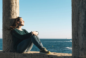 Spanien, Costa Brava, Sant Feliu de Guixols, Frau ruht sich in einer Laube am Meer bei Sonnenuntergang aus - GEMF000194