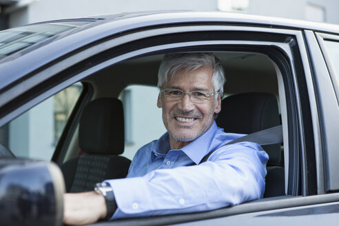 Porträt eines lächelnden Geschäftsmannes, der in seinem Auto sitzt - RBF002606