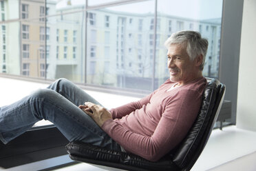 Man relaxing in a leather chair at home - RBF002656