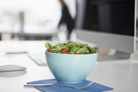 Bowl with garnished salad on a desk in an office stock photo