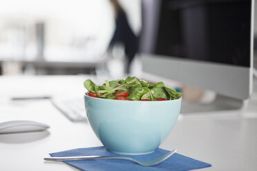 Bowl with garnished salad on a desk in an office - RBF002611