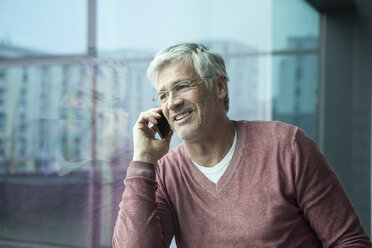 Portrait of smiling man telephoning with smartphone - RBF002625