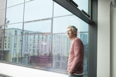 Mann schaut durch ein Fenster, lizenzfreies Stockfoto