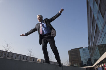 Businessman balancing on a wall - RBF002641