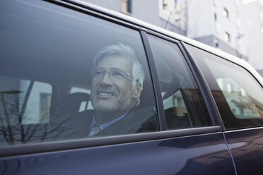 Lächelnder Geschäftsmann schaut durch das Fenster seines Autos - RBF002650