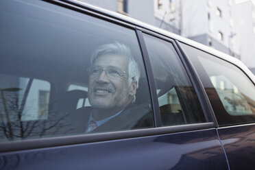 Smiling businessman looking through window of his car - RBF002650