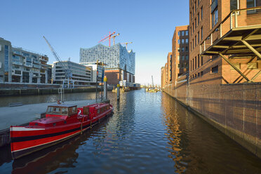 Deutschland, Hamburg, Blick auf die im Bau befindliche Elbphilharmonie mit vertäutem rotem Boot im Vordergund - RJF000424