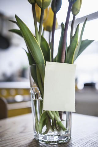 Klebezettel auf einem Glas mit Tulpen auf einem Küchentisch, lizenzfreies Stockfoto