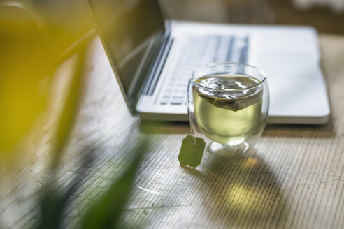 Glass of green tea beside laptop - RIBF000029