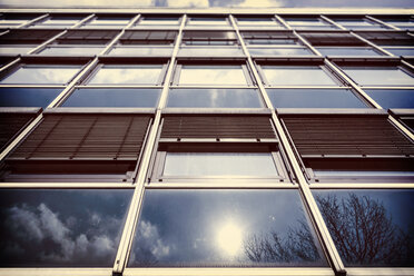 Deutschland, Bochum, Fassade eines Bürogebäudes mit Reflektionen von Sonne und Wolken - HOHF001342