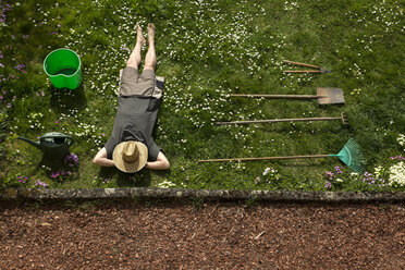 Mann liegt im Gras und entspannt sich bei der Gartenarbeit - MIDF000353