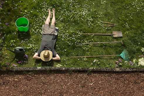 Man lying in grass relaxing from gardening - MIDF000353