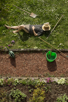 Man lying in grass relaxing from gardening - MIDF000354