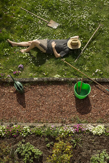 Mann liegt im Gras und entspannt sich bei der Gartenarbeit - MIDF000354