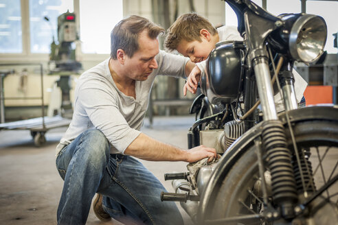 Father and son maintaining vintage moped - PAF001294