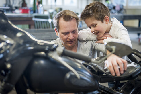 Father and son maintaining vintage moped - PAF001279