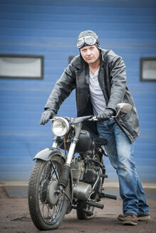 Mann mit Lederjacke, der ein altes Moped schiebt - PAF001282