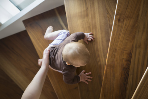 Die Hand der Mutter hilft dem kleinen Mädchen eine Treppe hinaufzusteigen, lizenzfreies Stockfoto