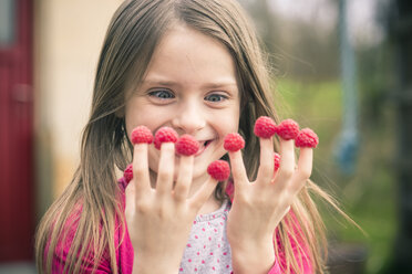 Happy girl with raspberries on her fingers - SARF001715