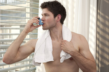 Young man using asthma inhaler - DHLF000527