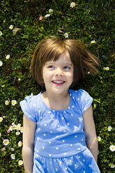 Porträt eines lächelnden kleinen Mädchens, das auf einer Wiese liegt - LVF003196
