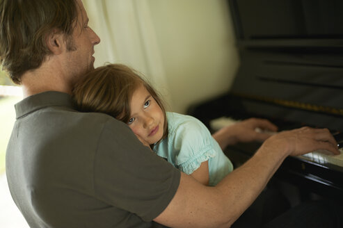 Father playing piano with daughter on his lap - MAO000036