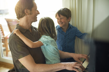 Vater spielt Klavier mit Tochter auf seinem Schoß, Sohn schaut zu - MAO000037