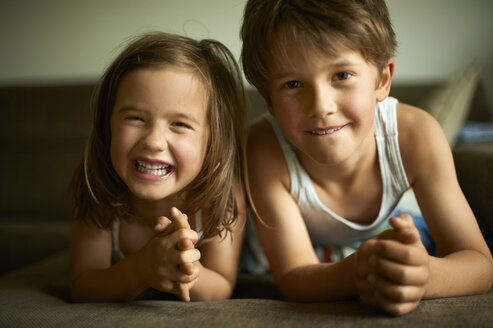 Brother and sister lying on floor smiling happily - MAO000048