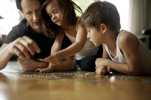Vater spielt mit seinen Kindern, die auf dem Boden liegen - MAO000052